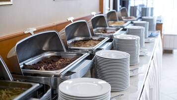 A buffet setup with multiple food stations and stacked plates.