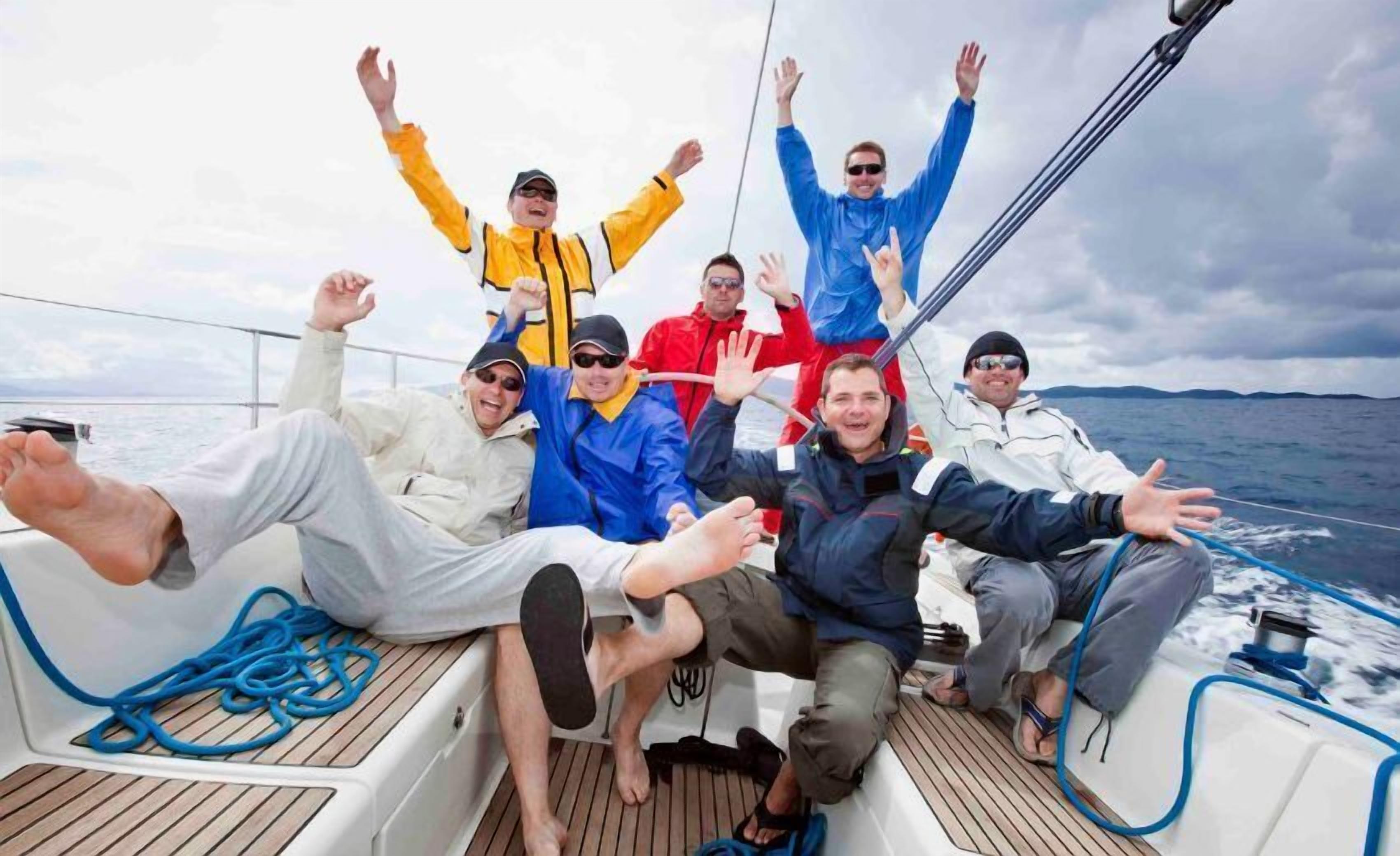 A group of people on a boat with a wooden deck and blue ropes.