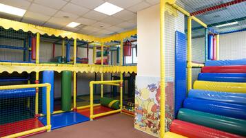 A multi-level indoor play area with netted walls and padded flooring.
