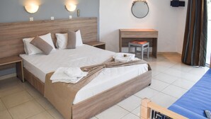 A neatly made bed with a wooden headboard, a bedside table, a small desk with a chair, and a wall-mounted mirror. - White Palace Studios (Rhodes)