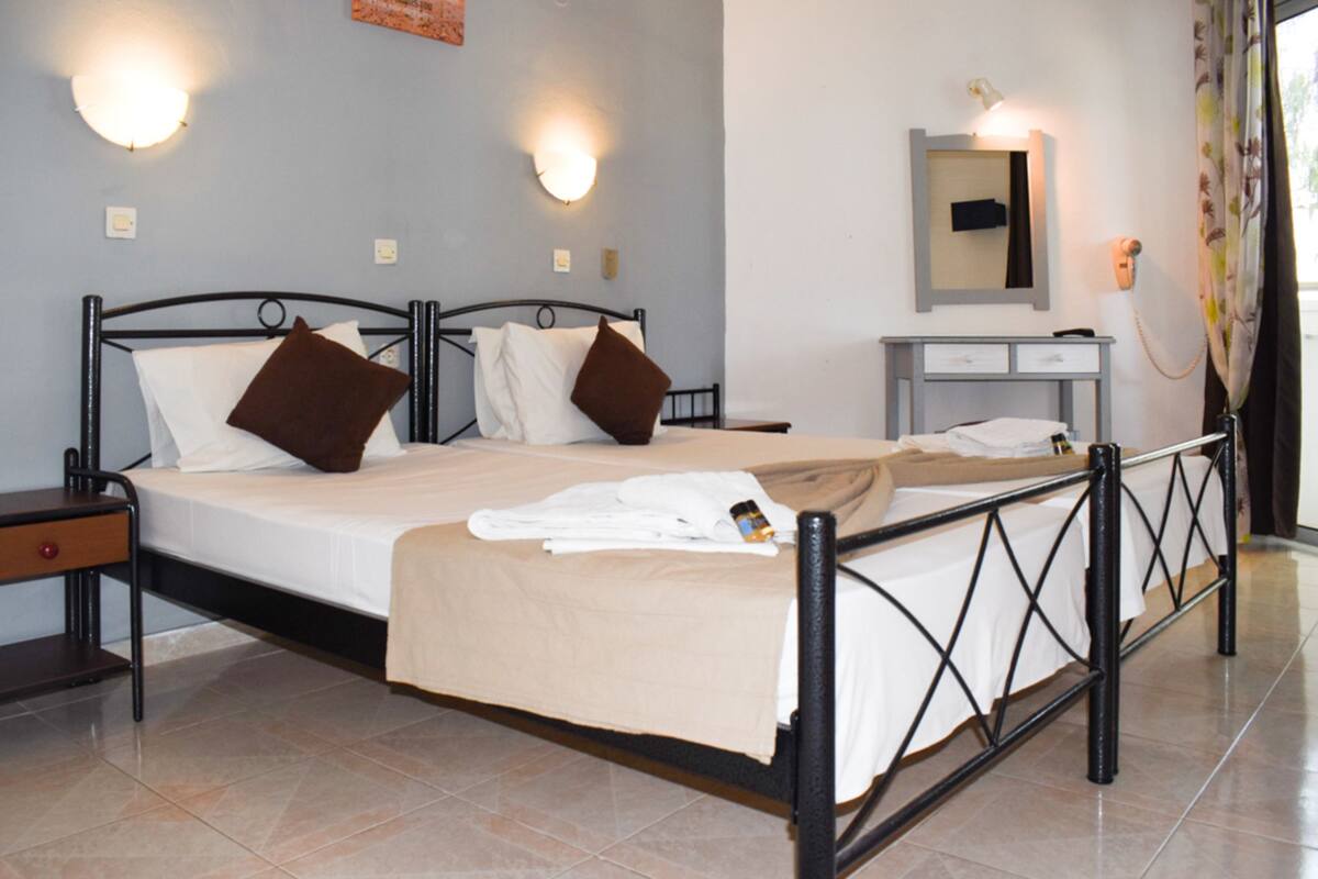 A hotel room with a bed, bedside tables, a desk, and a mirror.