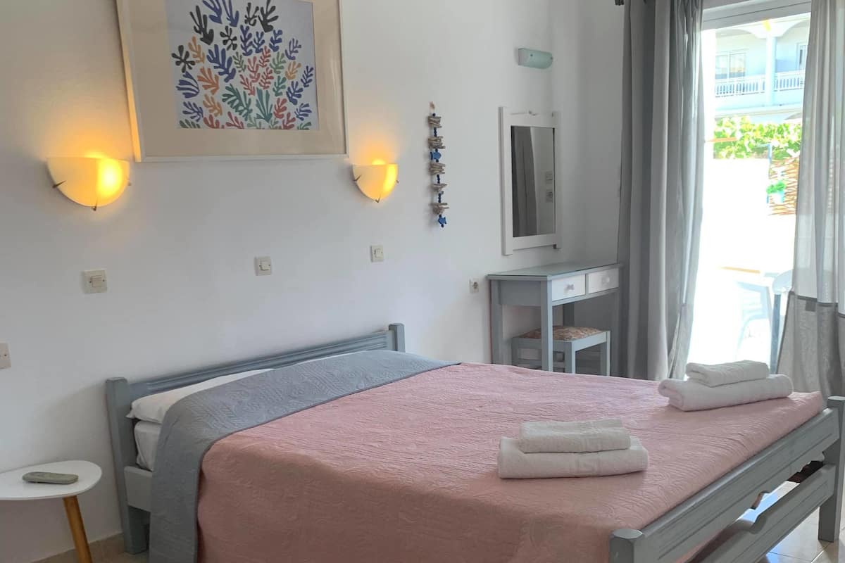 A neatly arranged bedroom with a bed, bedside table, and a small desk.
