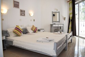A bedroom with a bed, bedside tables, a mirror, and a window with curtains. - White Palace Studios (Rhodes)