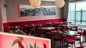 A restaurant with red booths, round tables, and hanging spherical light fixtures.