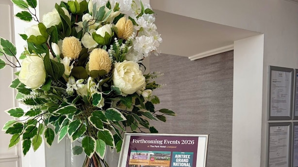Una recepción con un arreglo floral y un folleto con información sobre próximos eventos en The Park Hotel Liverpool.
