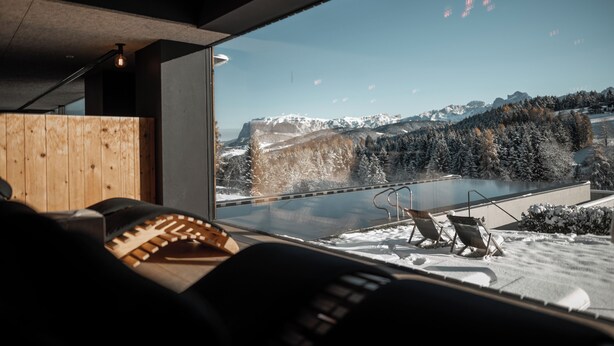 Un interior moderno con un amplio ventanal con vistas a un paisaje montañoso nevado.