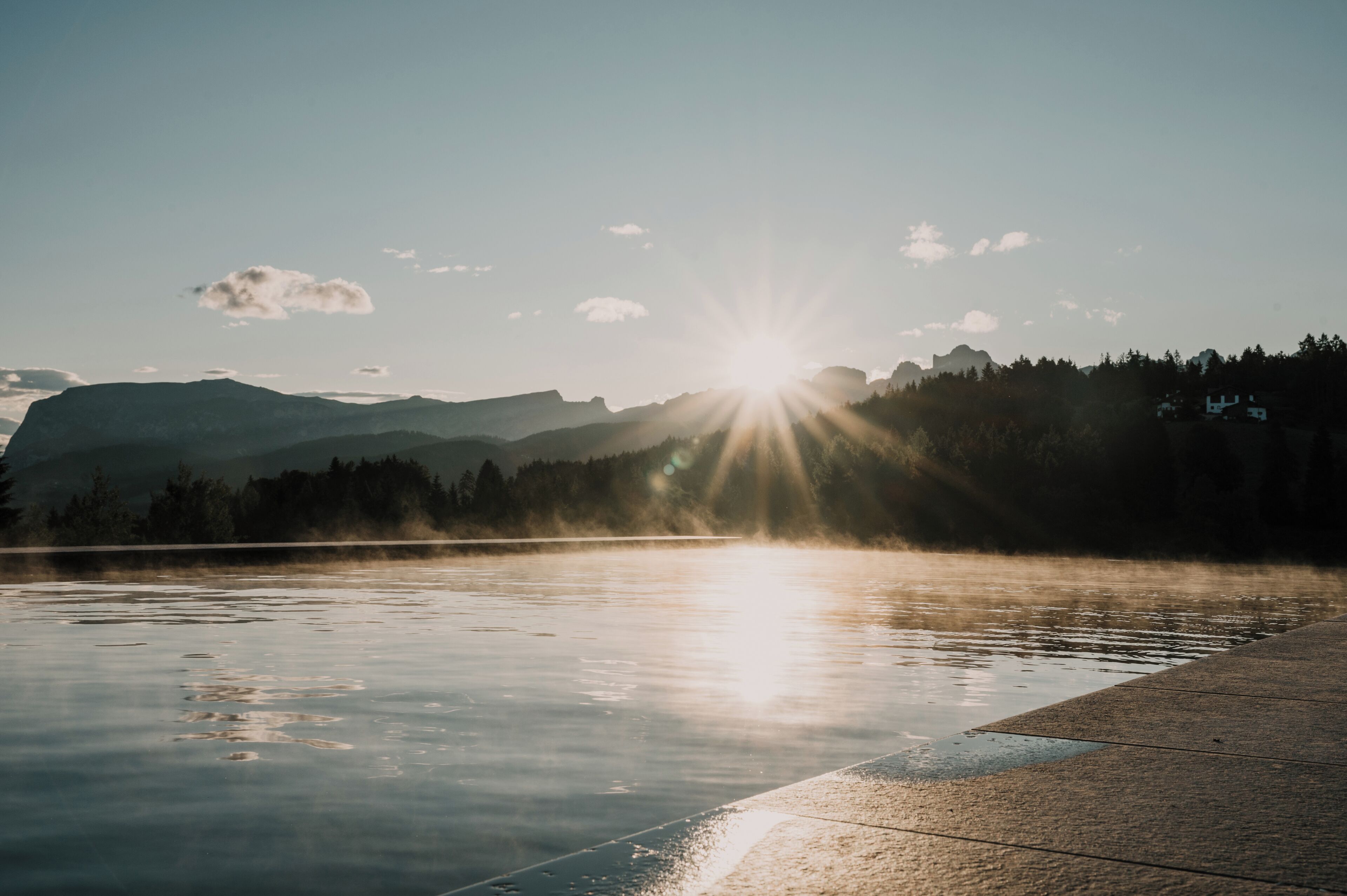 Um lago calmo com montanhas ao fundo e céu claro.