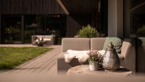 Un espacio al aire libre con asientos, un sofá y una mesa, un jarrón decorativo y una planta en maceta.