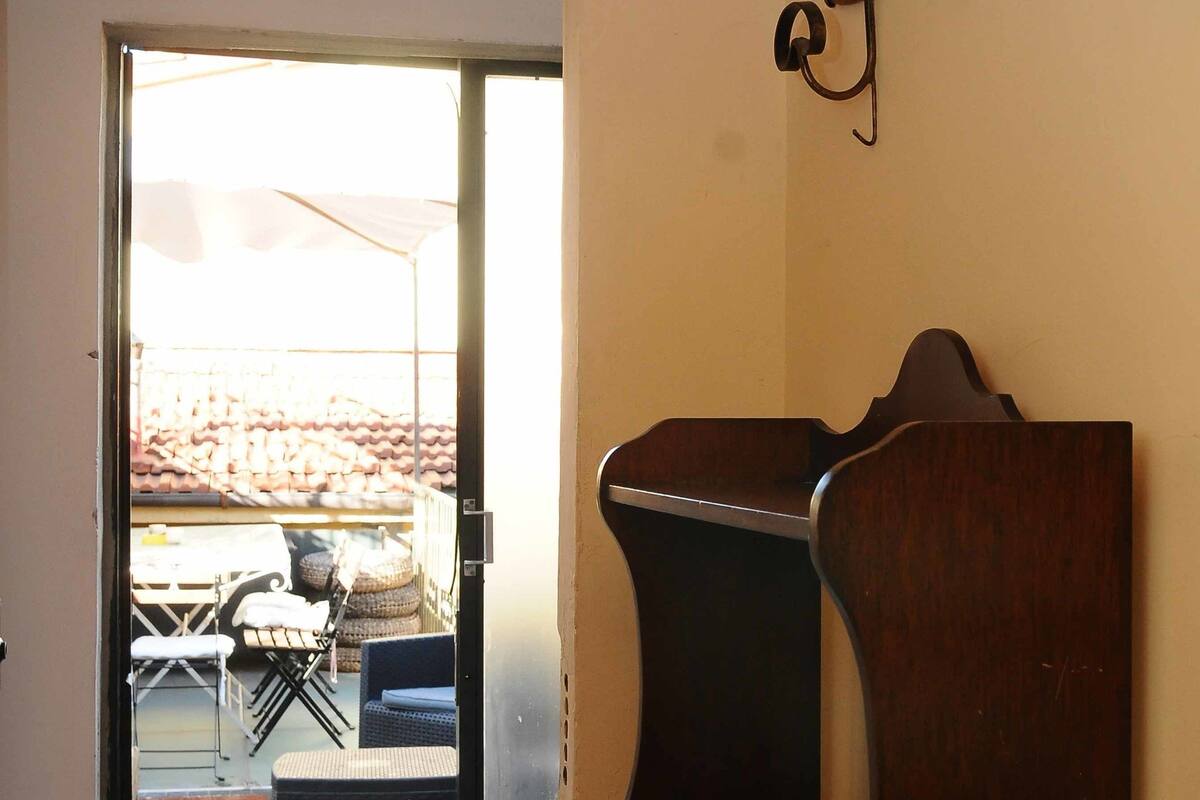 An open door leading to an outdoor patio with a table and chairs, and a wooden bench inside.