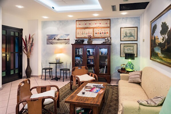 Un salon confortable avec un canapé, des fauteuils, une table basse et une bibliothèque.