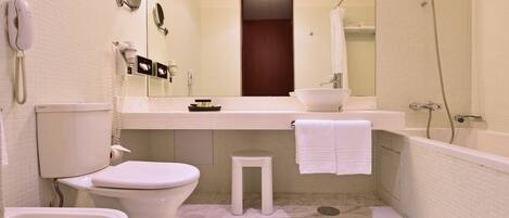 A bathroom with a toilet, bidet, sink, and bathtub.