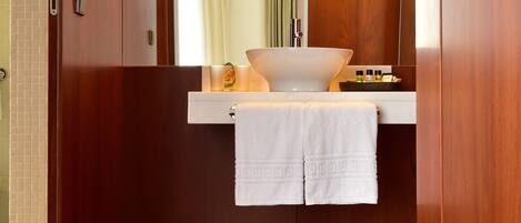 A modern bathroom with a wooden vanity, a large mirror, and a white sink.