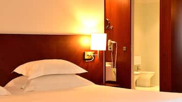 A hotel room with a bed, a bedside telephone, and a visible bathroom with a toilet and sink.