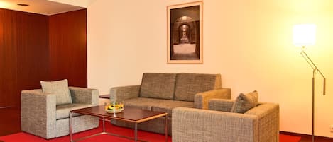 Una sala moderna con un sofá gris, una mesa de centro y una alfombra roja.
