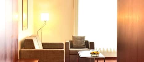 A modern living room with two sofas, a coffee table, and a red rug.