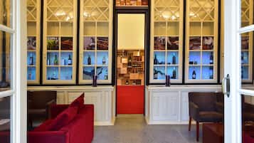 Vestíbulo de hotel con alfombra roja, zona de estar y vitrinas para exhibir vinos.
