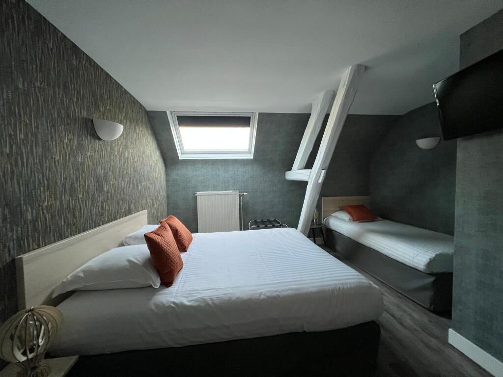 Une chambre d’hôtel de taille réduite, avec un lit superposé, une petite fenêtre et un radiateur.