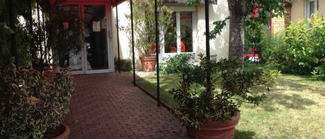 A covered outdoor area with a brick pathway leading to a building entrance.