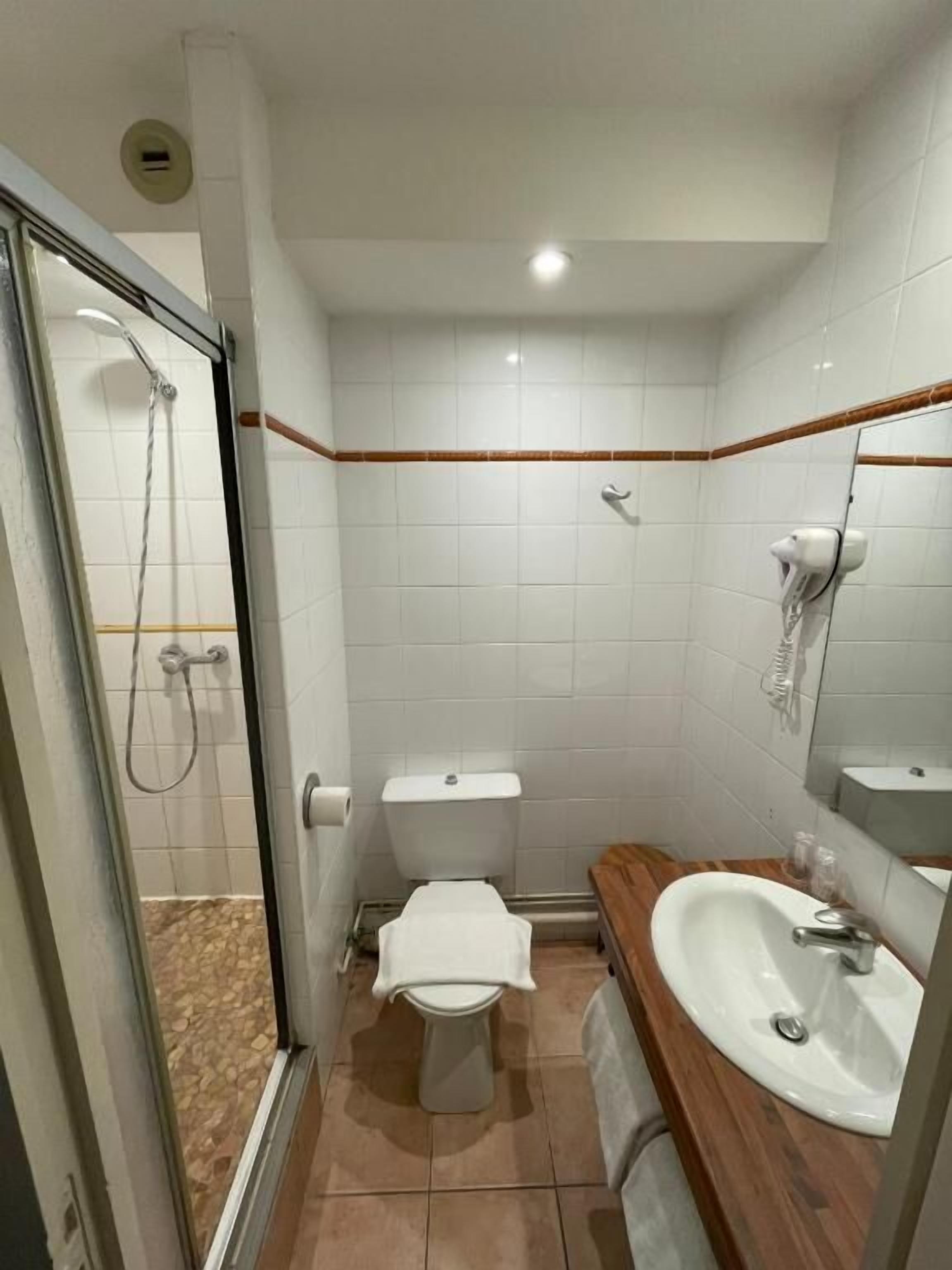 Une salle de bain avec une douche à parois de verre, des toilettes, un lavabo et un miroir.