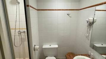 Une salle de bain avec une douche à parois de verre, des toilettes, un lavabo et un miroir.