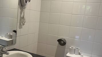 Un baño con lavamanos blanco, un espejo, toallero, inodoro y zona de ducha.