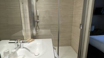 Une salle de bain moderne avec un lavabo blanc, une douche en verre et un revêtement de sol en bois.