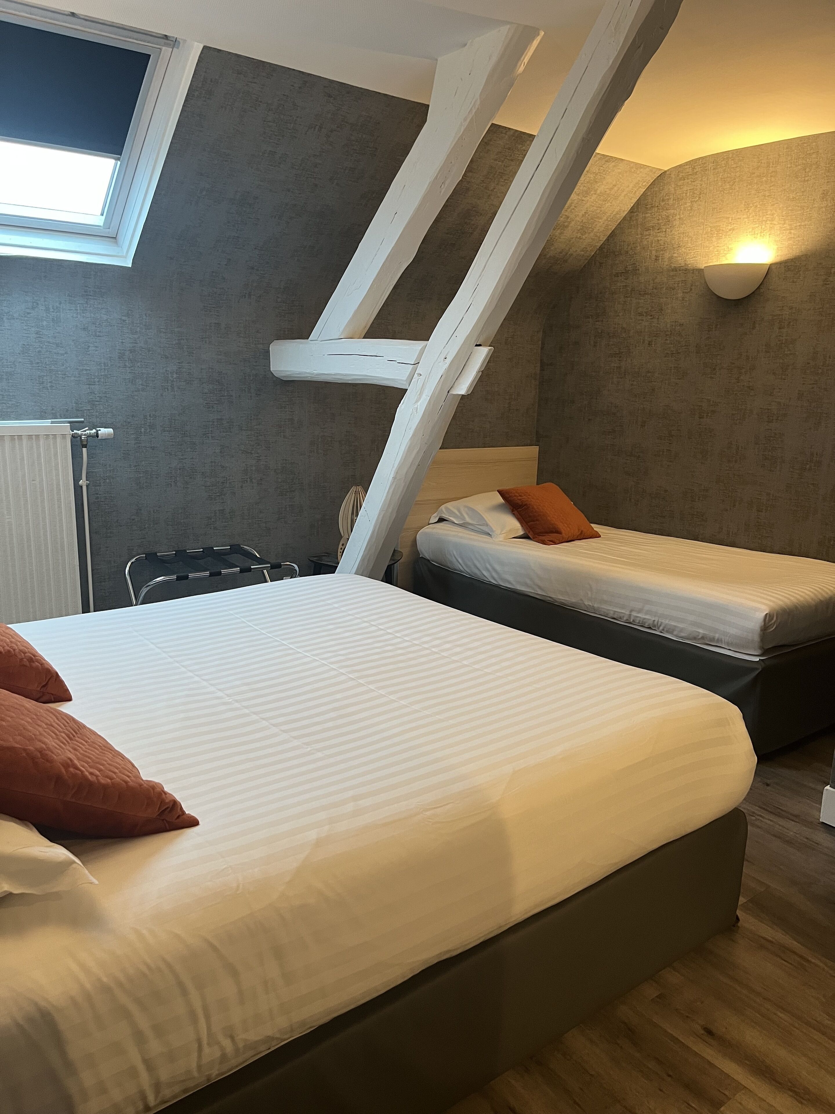 A bedroom with two beds, a window, and a sloped ceiling.