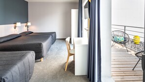 A hotel room with two beds, a desk, a chair, and a balcony with a chair and a yellow lantern. - Hôtel Mirasol (Lourdes)