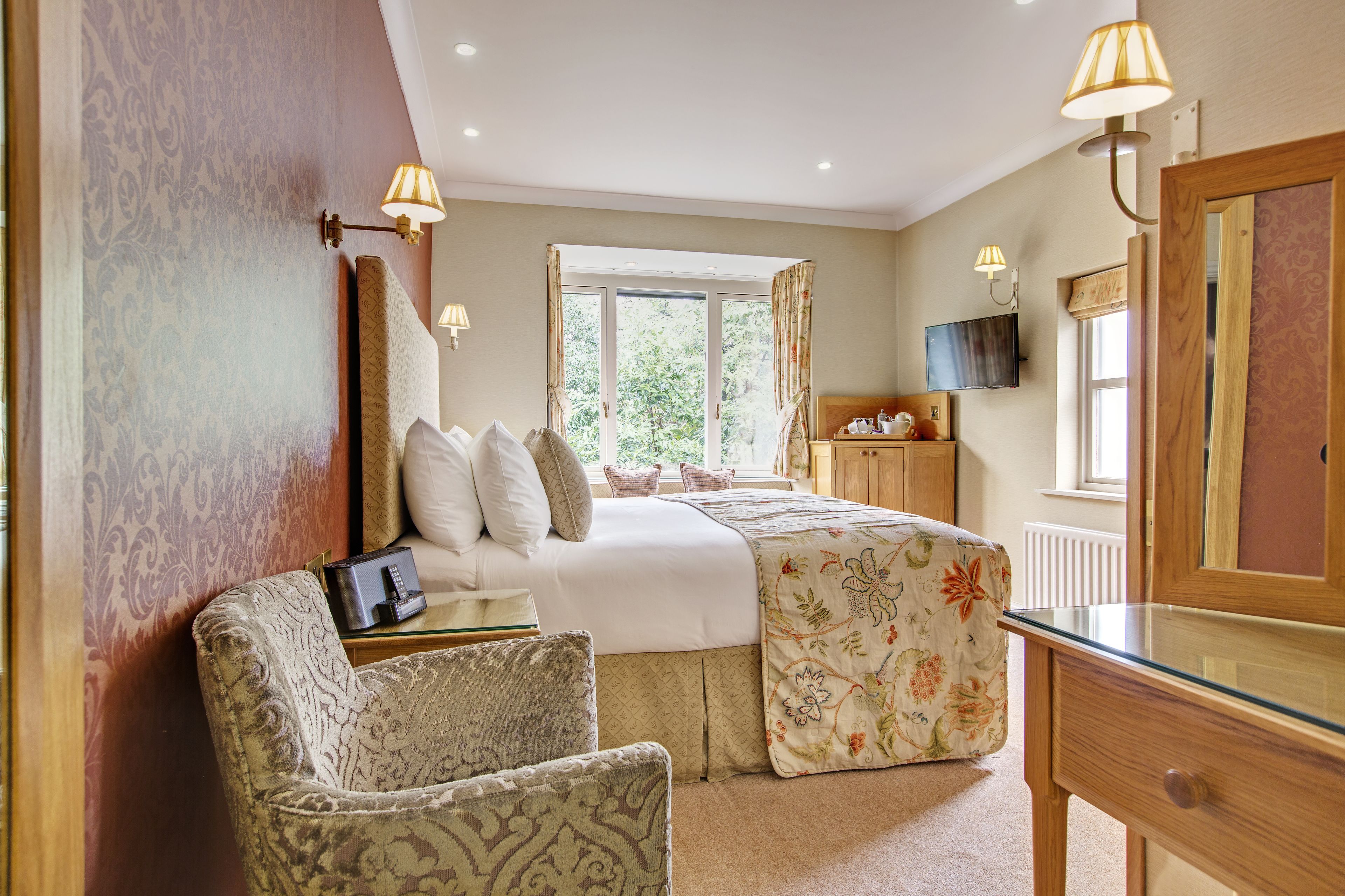 A bedroom with a bed, bedside table, lamp, chair, and a dresser.