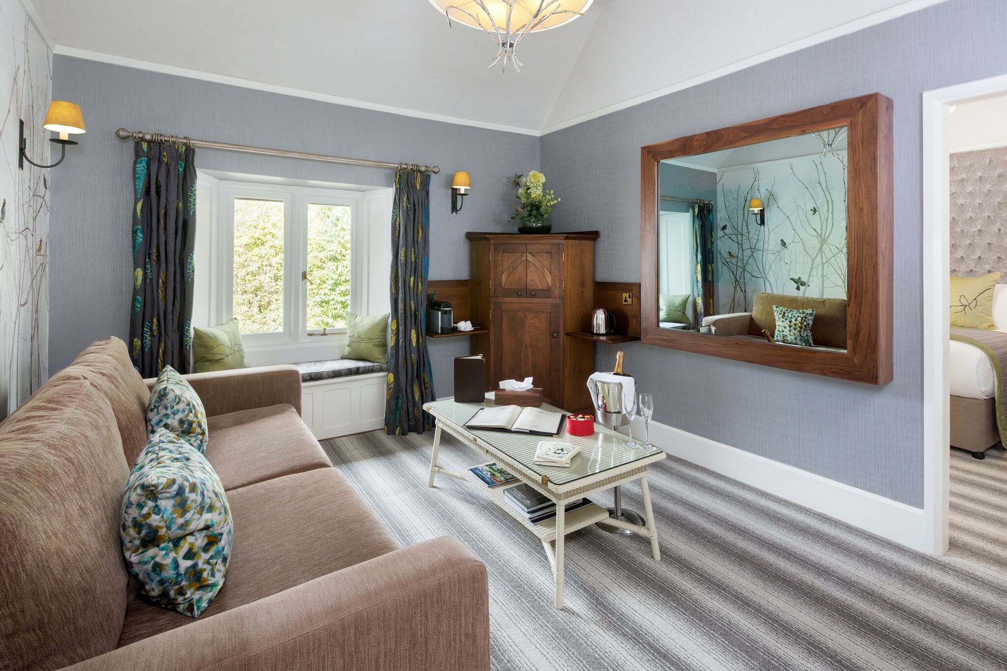 A living room with a sofa, a glass coffee table, a wooden cabinet, and a large mirror.
