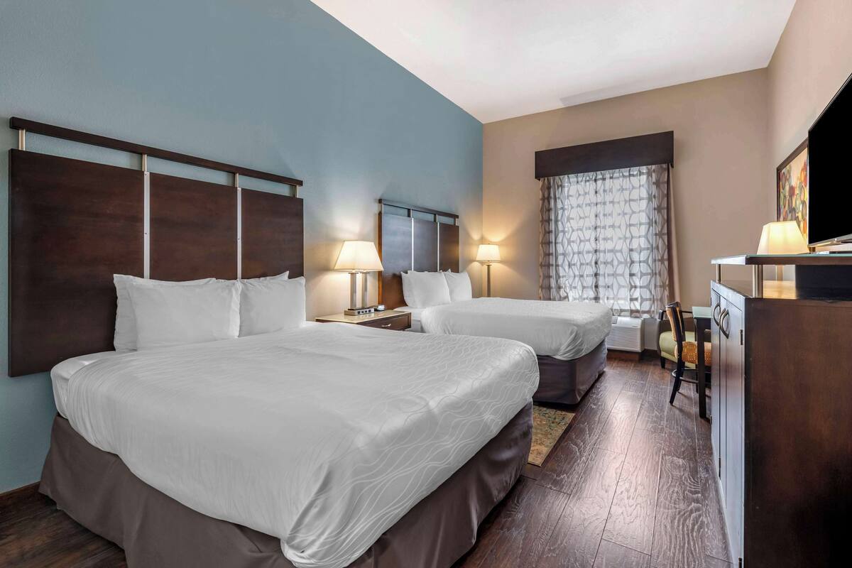 Een hotelkamer met twee bedden, een bureau, een stoel en een televisie.
