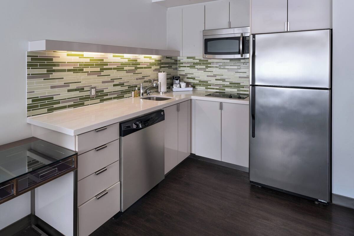 A modern kitchen with a dishwasher, stainless steel refrigerator, and a microwave.