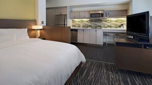 Une chambre d’hôtel équipée d’un lit, d’un bureau, d’une télévision, d’un four à micro-ondes et d’une kitchenette.