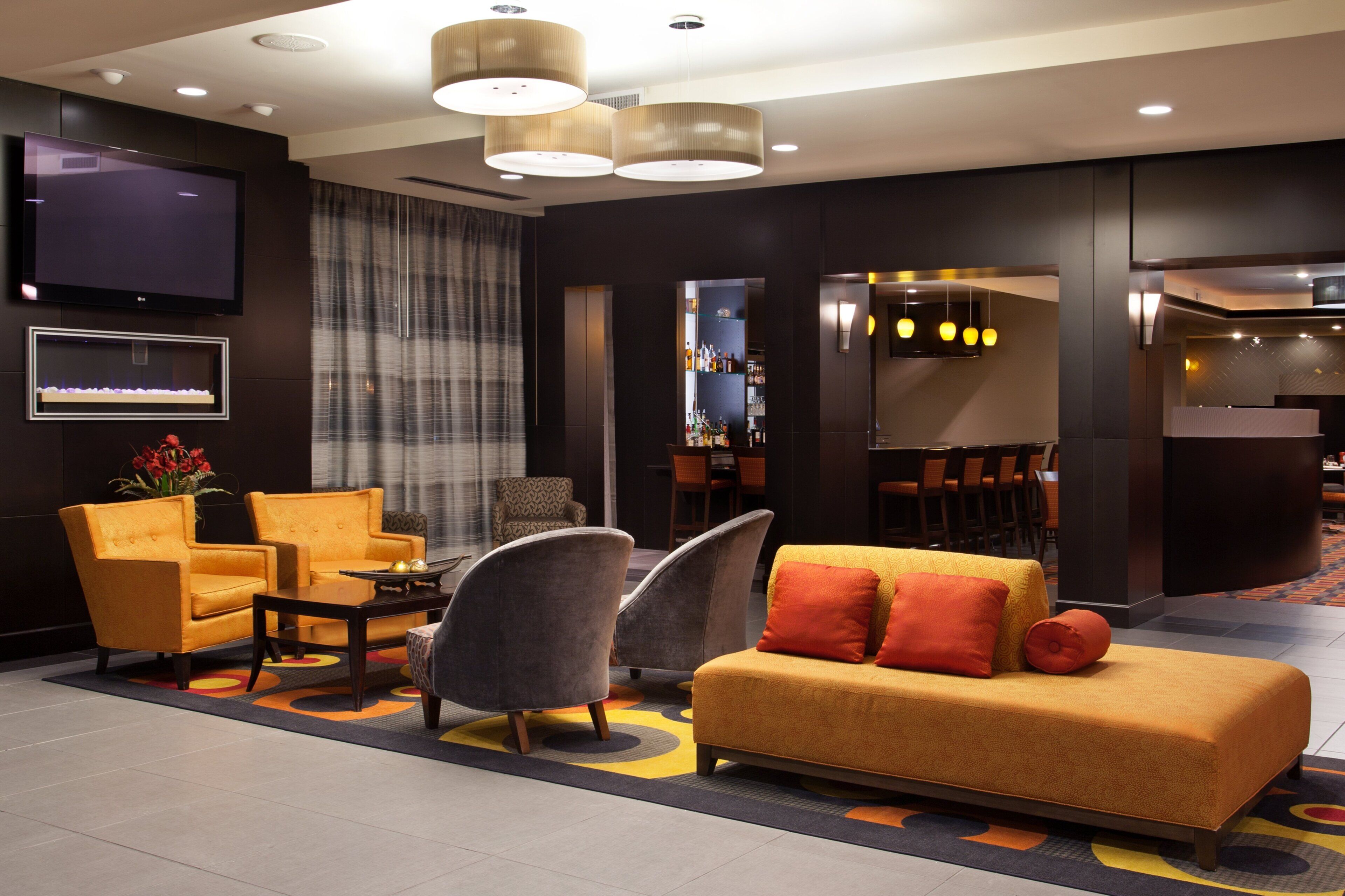 Et hotel lobby med siddeområde, bar og fjernsyn.