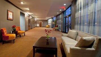 Un hall de hotel con mostrador de recepción, zona de estar y amplias ventanas.
