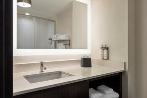 A modern bathroom with a large mirror, a sink, and a towel rack.