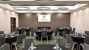 A conference room with round tables, chairs, and water bottles.