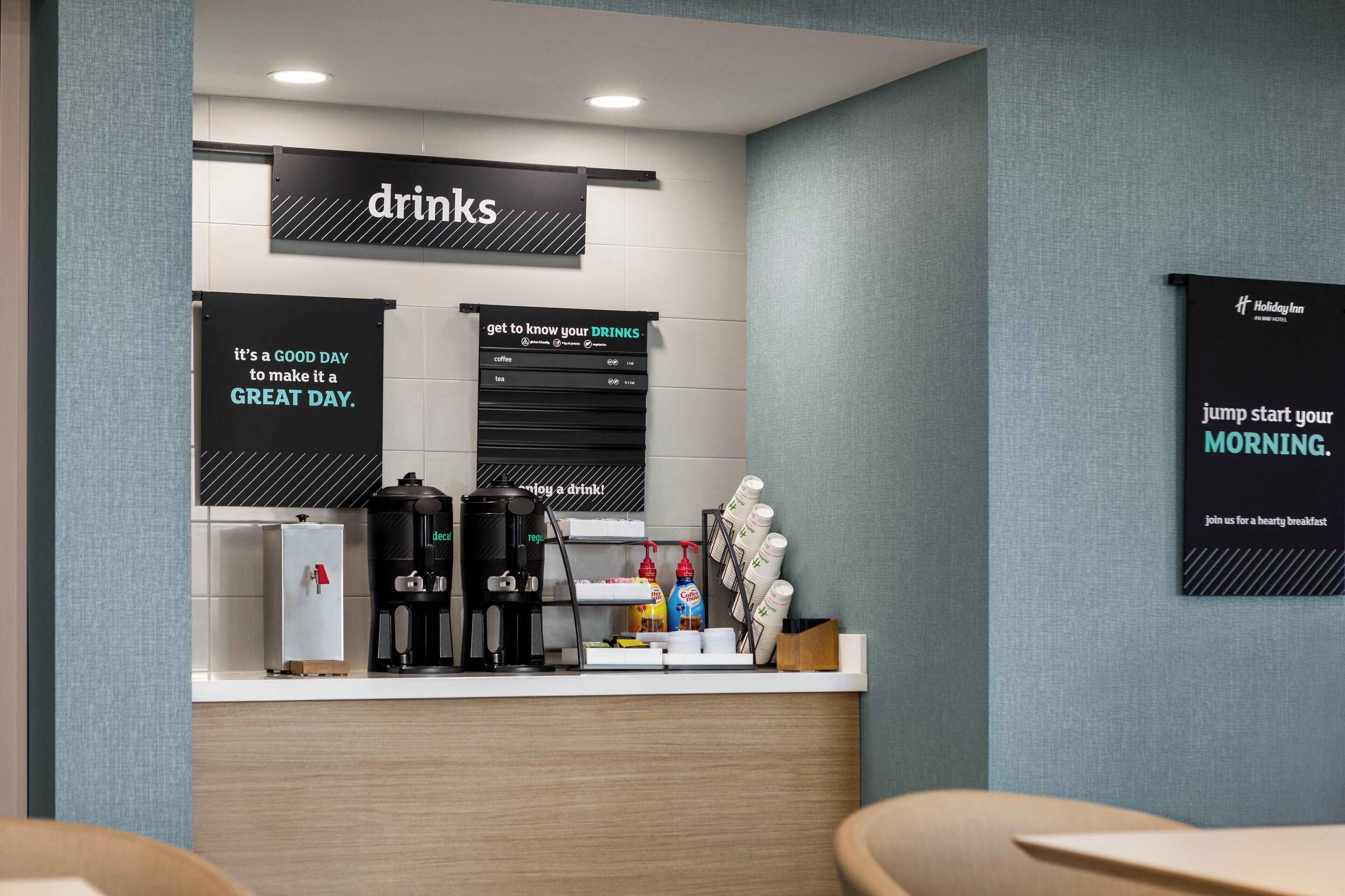 A modern hotel reception area with a coffee station, a refrigerator, and a coffee machine.
