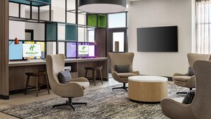 A modern hotel lobby with a reception desk, comfortable seating, a large flat-screen TV, and a contemporary design. - Holiday Inn Columbus-Hilliard by IHG (Columbus)