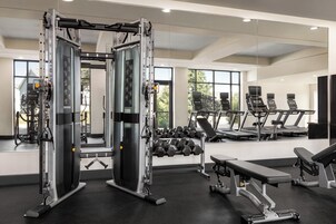 A gym with weight machines, dumbbells, treadmills, and benches.