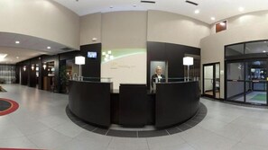A reception area with a curved desk, a receptionist, and a digital screen.