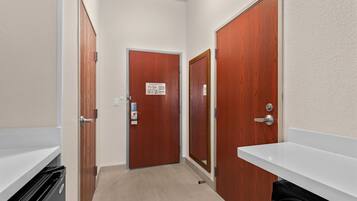 A narrow hallway with wooden doors and a white sink.