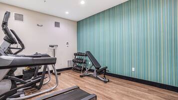 A gym with exercise equipment including treadmills, a bench, and dumbbells.