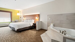 A modern hotel room with a large bed, a separate bathroom with a bathtub, and a window with blinds. - Holiday Inn Express Suites Van Buren-Ft Smith Area by IHG (Van Buren)