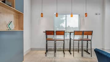 Un comedor moderno con una mesa y sillas de madera, vista a través de un ventanal e iluminación colgante.
