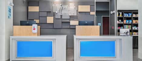 A reception area with two reception desks, a wall-mounted sign, and a snack vending machine.