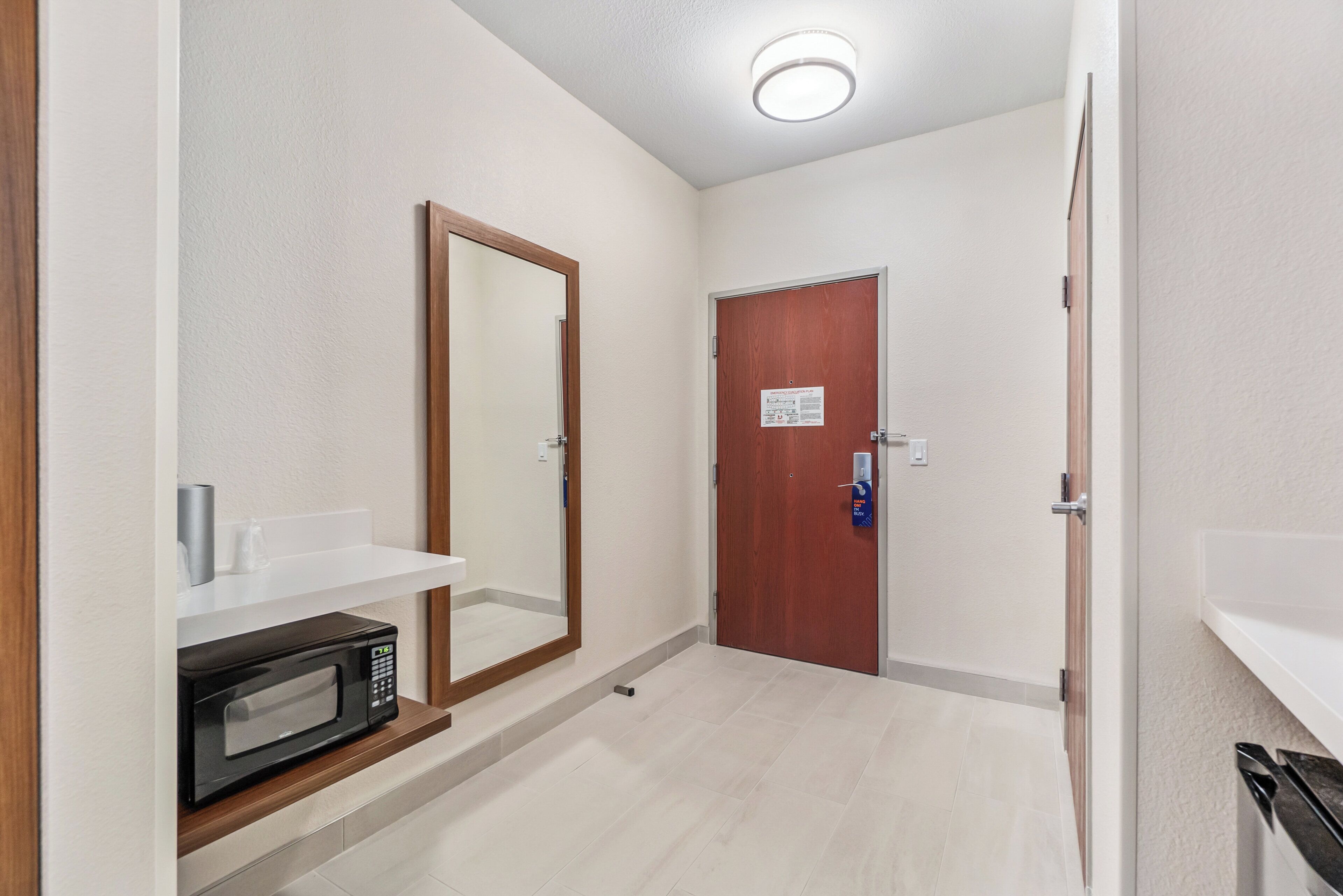 Un pasillo con microondas, espejo y una puerta con un letrero.