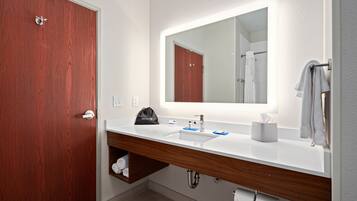 A modern bathroom with a wooden vanity, a large mirror, and a towel rack.