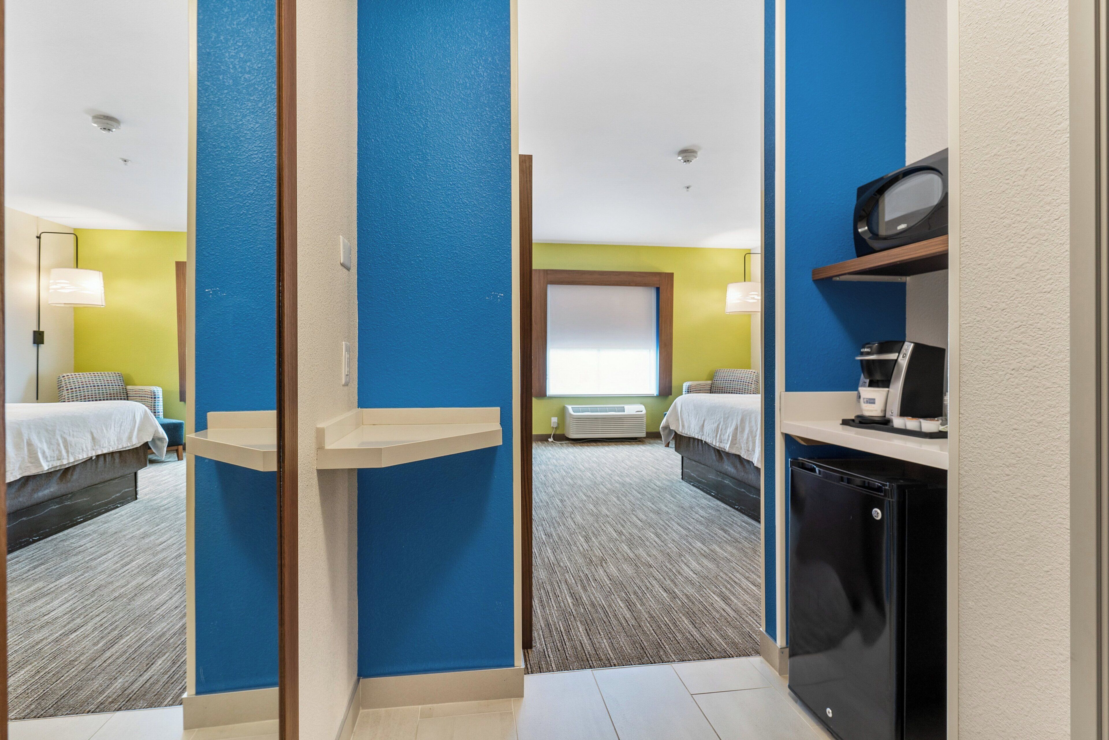 A hotel room with two beds, a desk with a coffee maker, and a microwave.