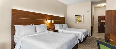 Een hotelkamer met twee bedden, een houten hoofdbord, een nachtkastje en een schilderij aan de muur.